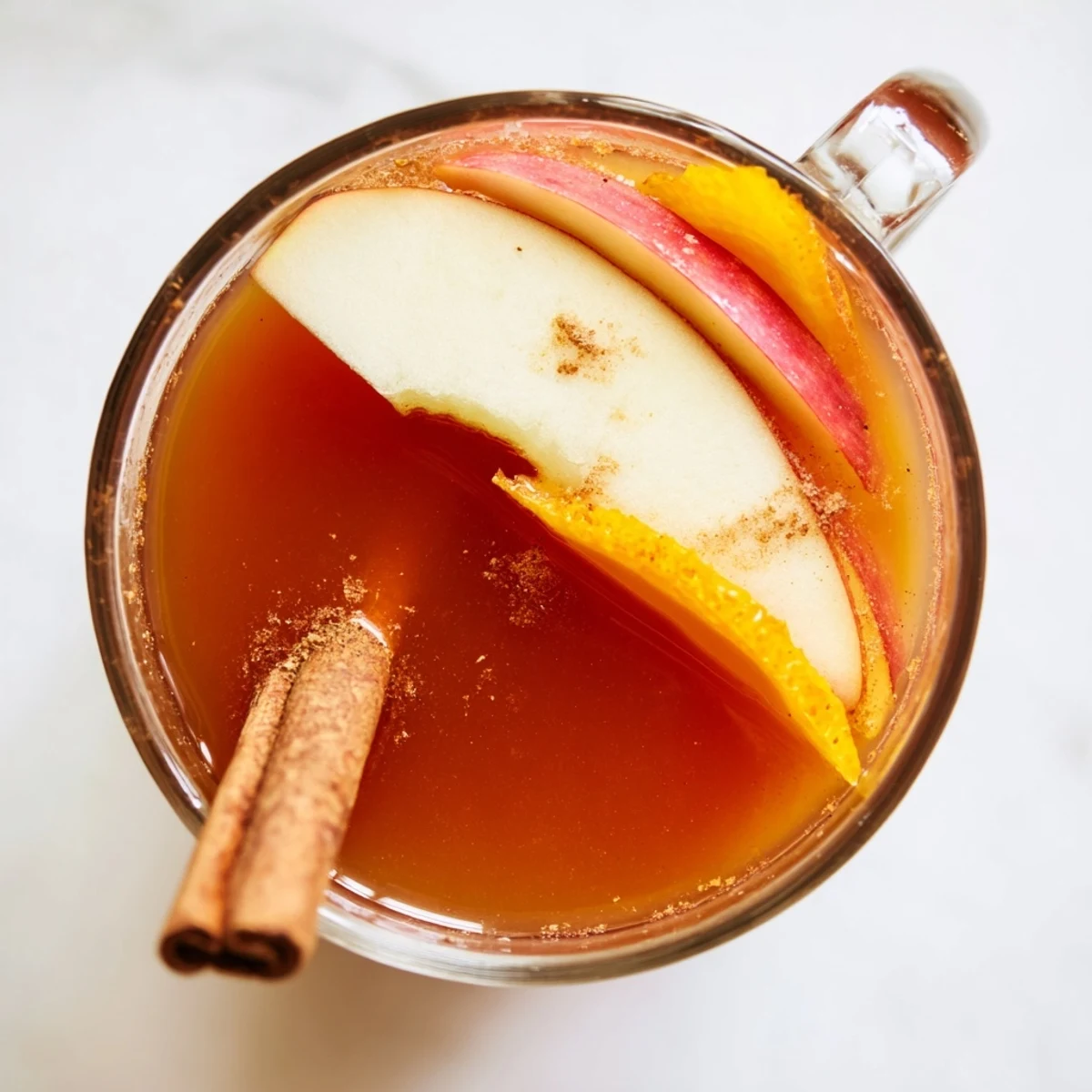 Steaming mugs of Spiced Apple Cider, garnished with apples and cinnamon, aromatically inviting.