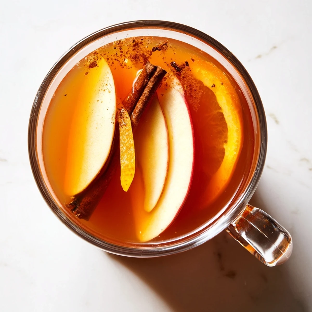 Enjoy hot, flavorful Spiced Apple Cider in clear mugs, showcasing the amber color and spices.