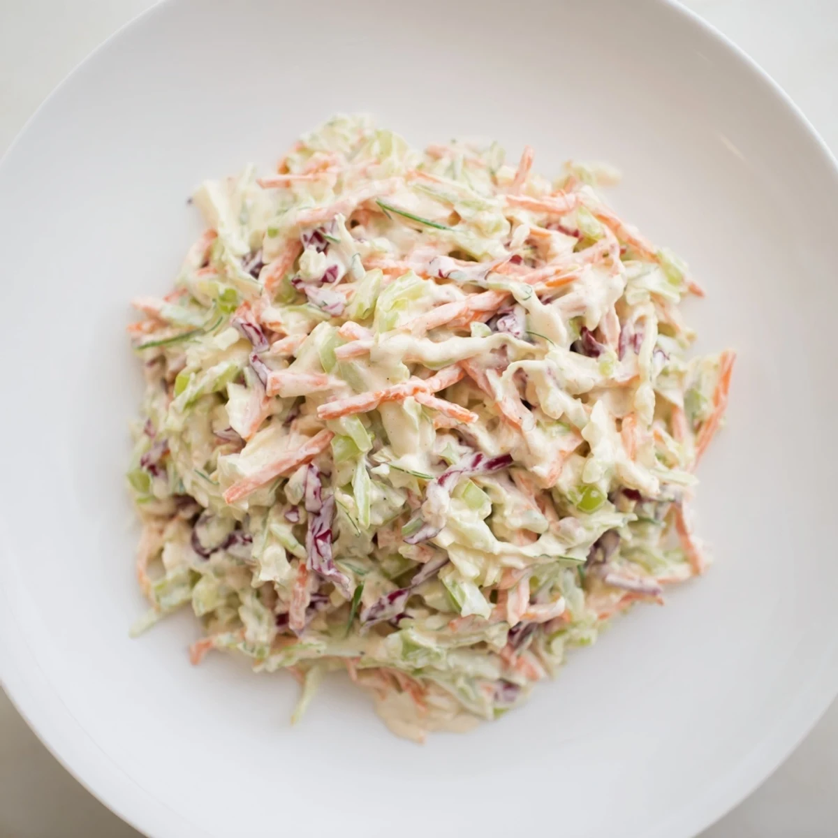 Creamy coleslaw, a vibrant mix of shredded cabbage and carrots coated in a tangy dressing, ready to serve.