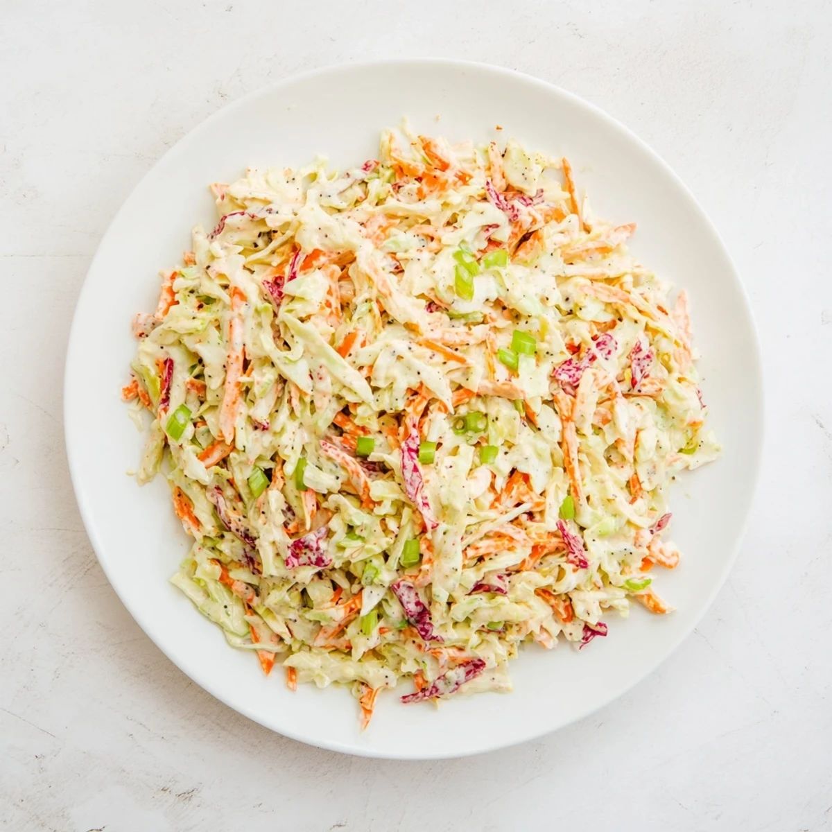 A bowl of delicious creamy coleslaw shows off a colorful mix of vegetables, ideal for summer picnics.