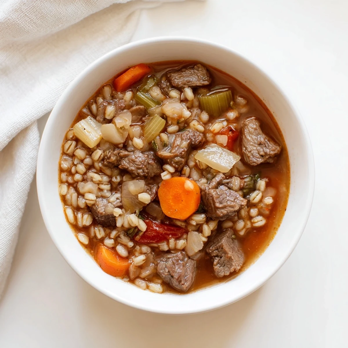 Close-up of golden Beef Barley Soup, ready for serving with crusty bread for a warm meal.