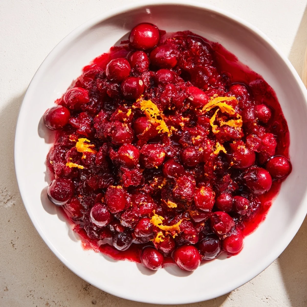 Warm, homemade cranberry compote simmering in a saucepan, hinting at a sweet and tangy flavour.