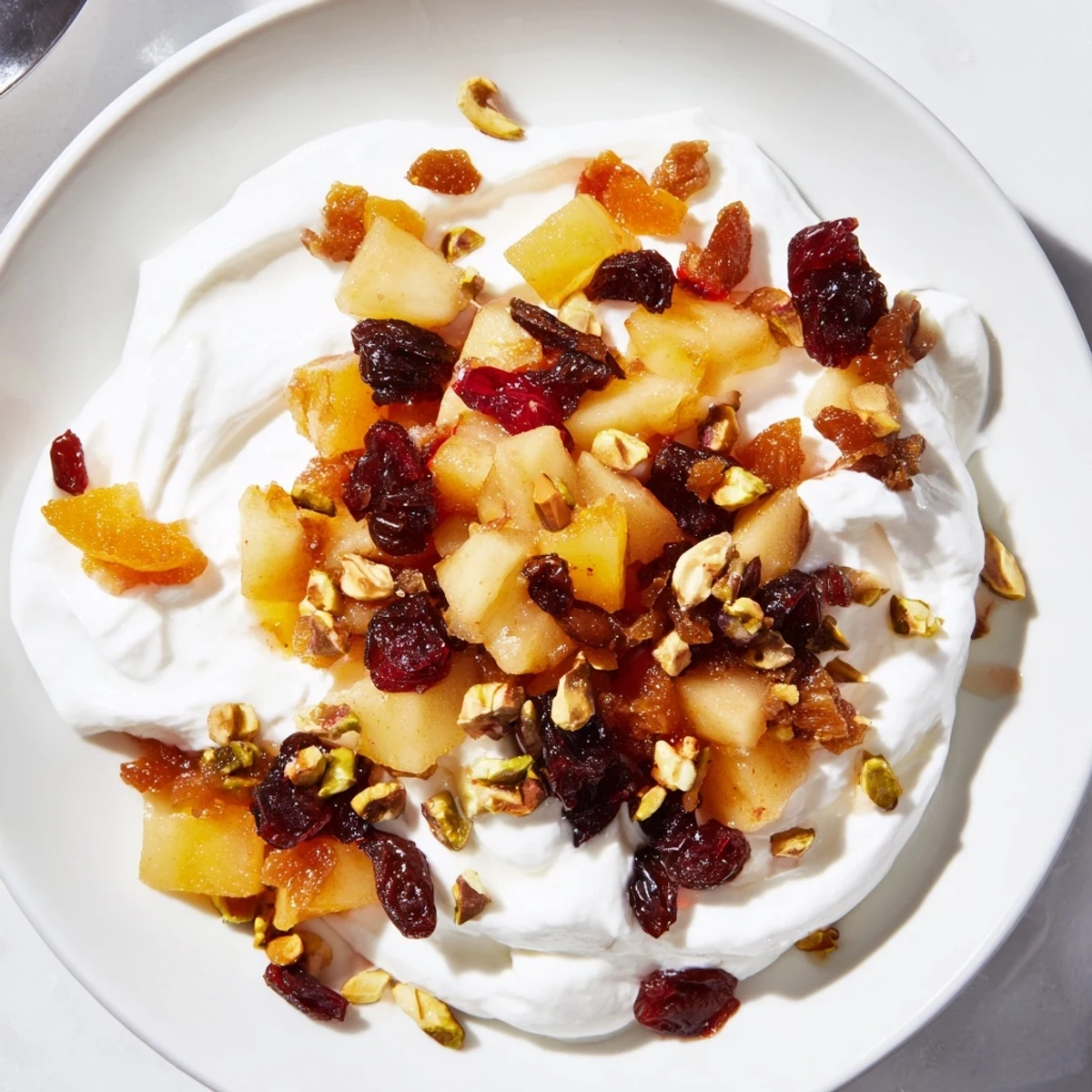 Warm Winter Fruit Compote beautifully spooned over creamy Greek yogurt, ready to enjoy.