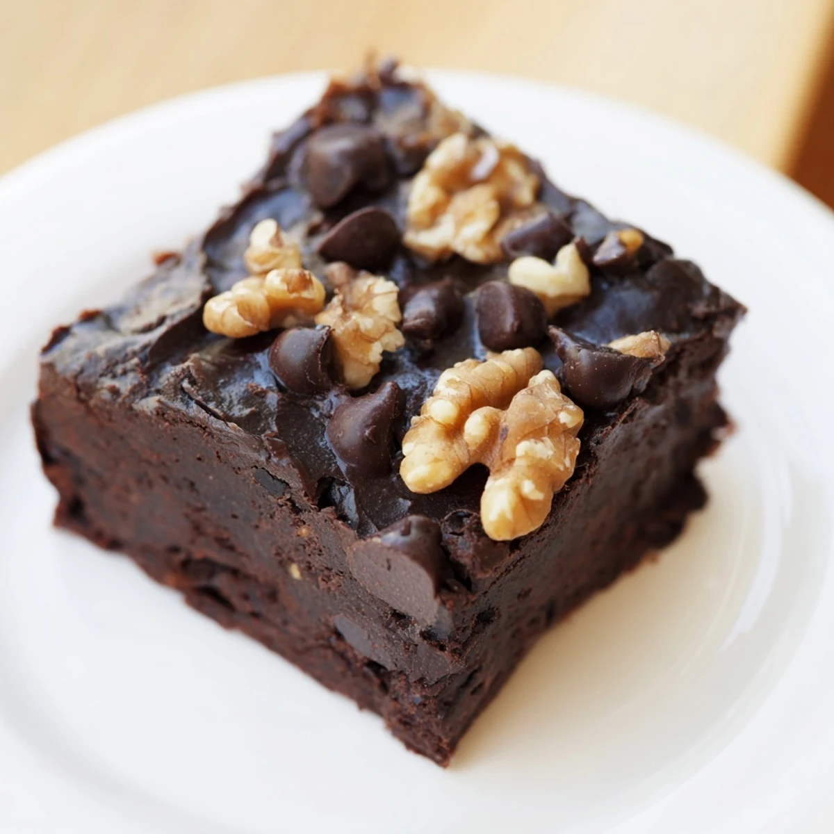 Sliced squares of rich Chocolate Fudge Brownies with Chopped Walnuts arranged on parchment, ready to serve with a cold glass of milk.