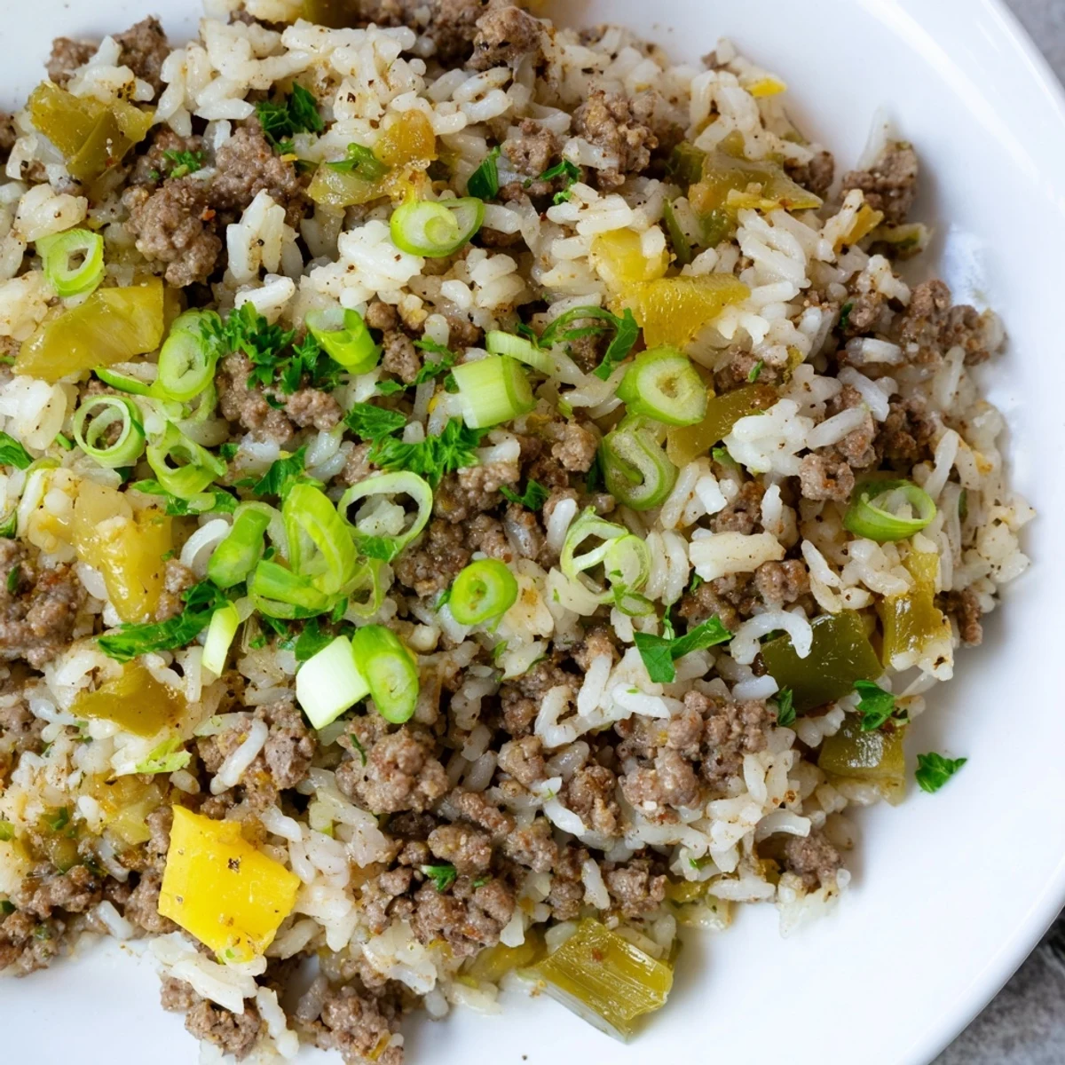 Savory Mardi Gras Dirty Rice with Beef steaming in a skillet, garnished with fresh parsley and green onions, perfect for a festive feast.