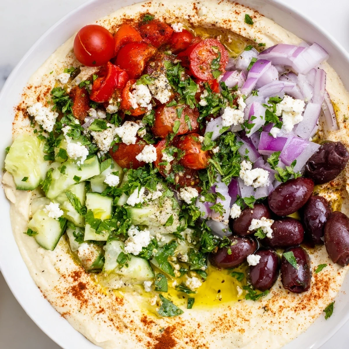 Vibrant Mediterranean Hummus Bowl featuring bright cherry tomatoes, diced cucumbers, and tangy feta, drizzled with olive oil and parsley.