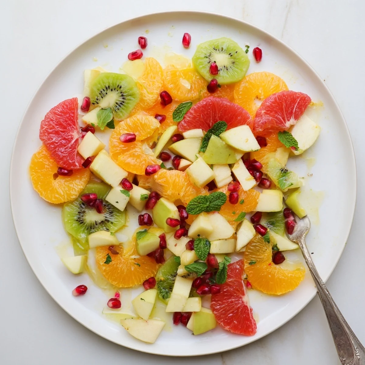 Freshly tossed Winter Fruit Salad with Mint features crisp apple and pear slices alongside green kiwi, offering a bright and refreshing vegan salad perfect for a healthy winter side.