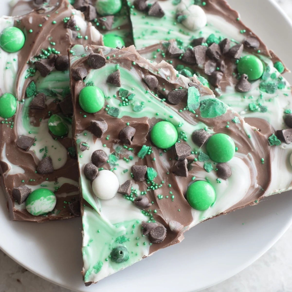 Homemade St. Patrick's Day Mint Chocolate Bark with marbled chocolate and mint candies on a baking sheet.