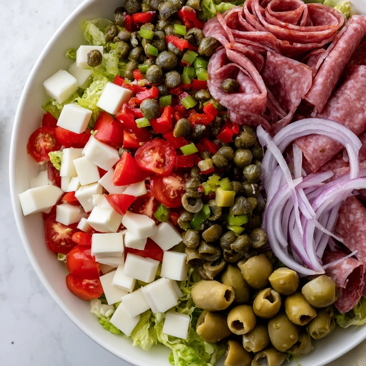 New Orleans Muffuletta Salad plated with romaine, salami, provolone, mozzarella, and a bright olive relish.
