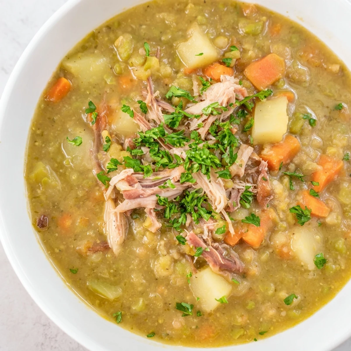 Hearty Green Split Pea Soup with Smoked Turkey Leg served hot in a rustic bowl, garnished with fresh parsley and a crusty bread slice.
