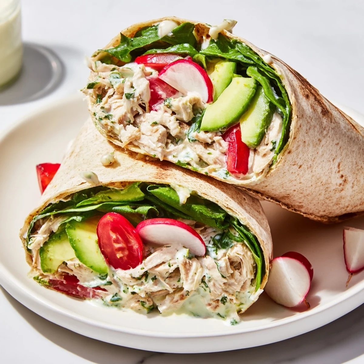 A vibrant wrap filling of Green Goddess Chicken Salad with diced chicken, creamy avocado slices, and crisp radishes on a rustic wooden table for a healthy dinner.