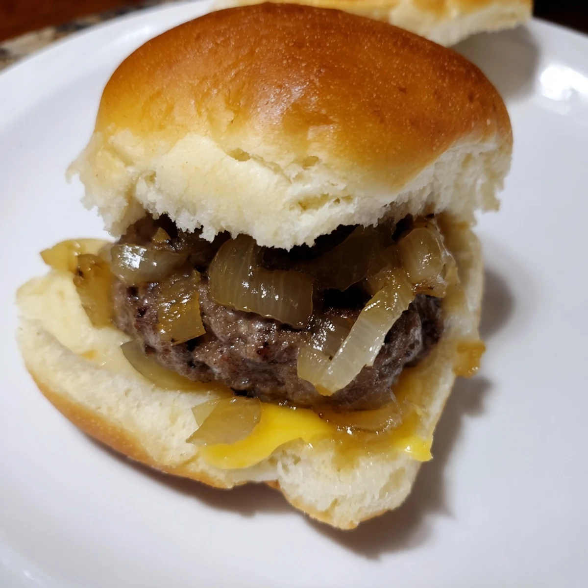 Juicy beef sliders with melted cheese and golden caramelized onions on soft toasted buns for a party.