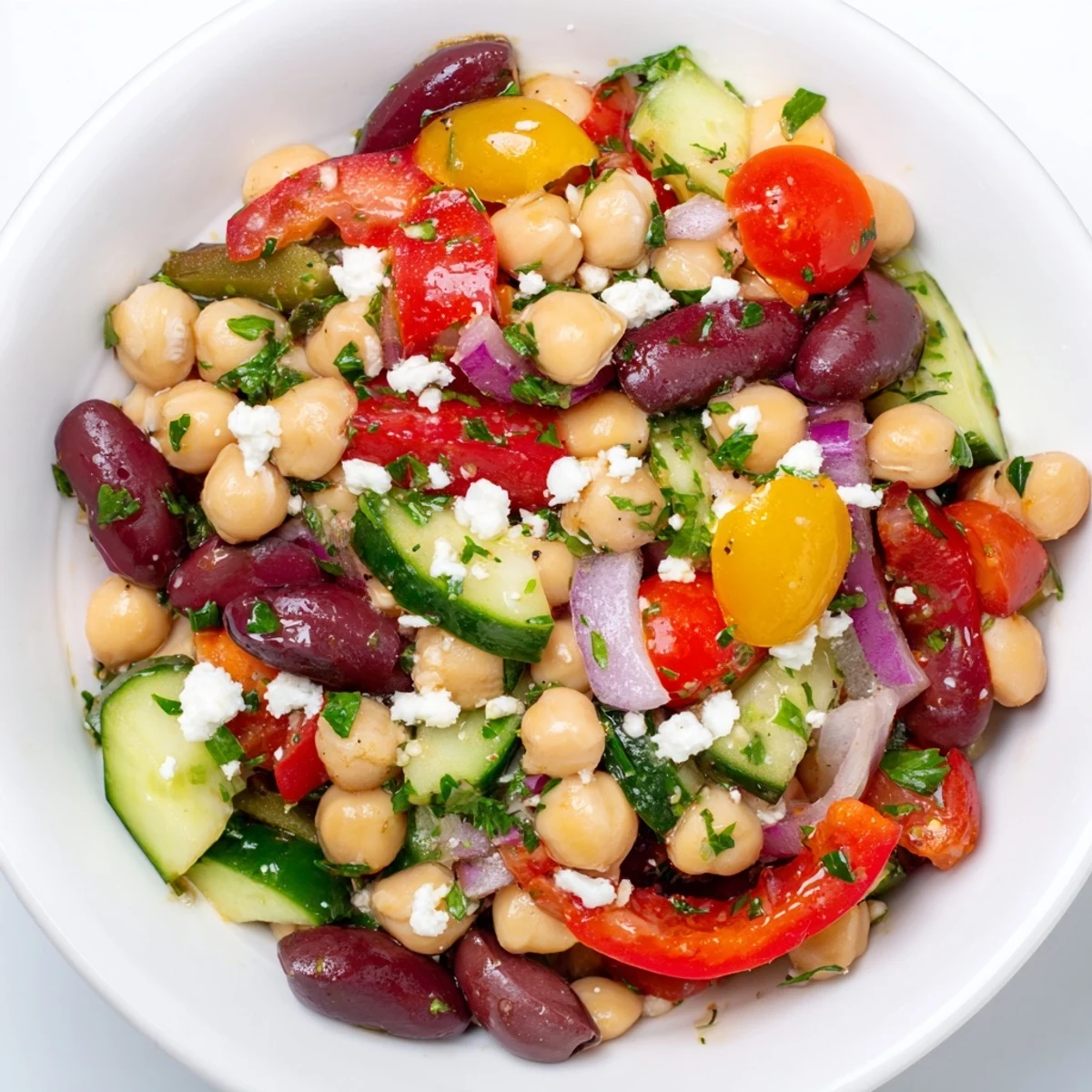 This Mediterranean Dense Bean Salad is served in a bowl with olives and fresh parsley.