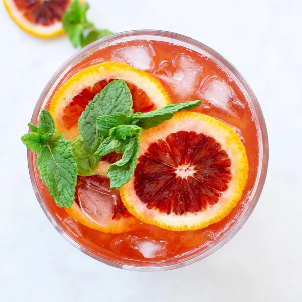 Close-up of Blood Orange Lemonade in a serving glass, showing vibrant color, condensation, and a refreshing citrus garnish.