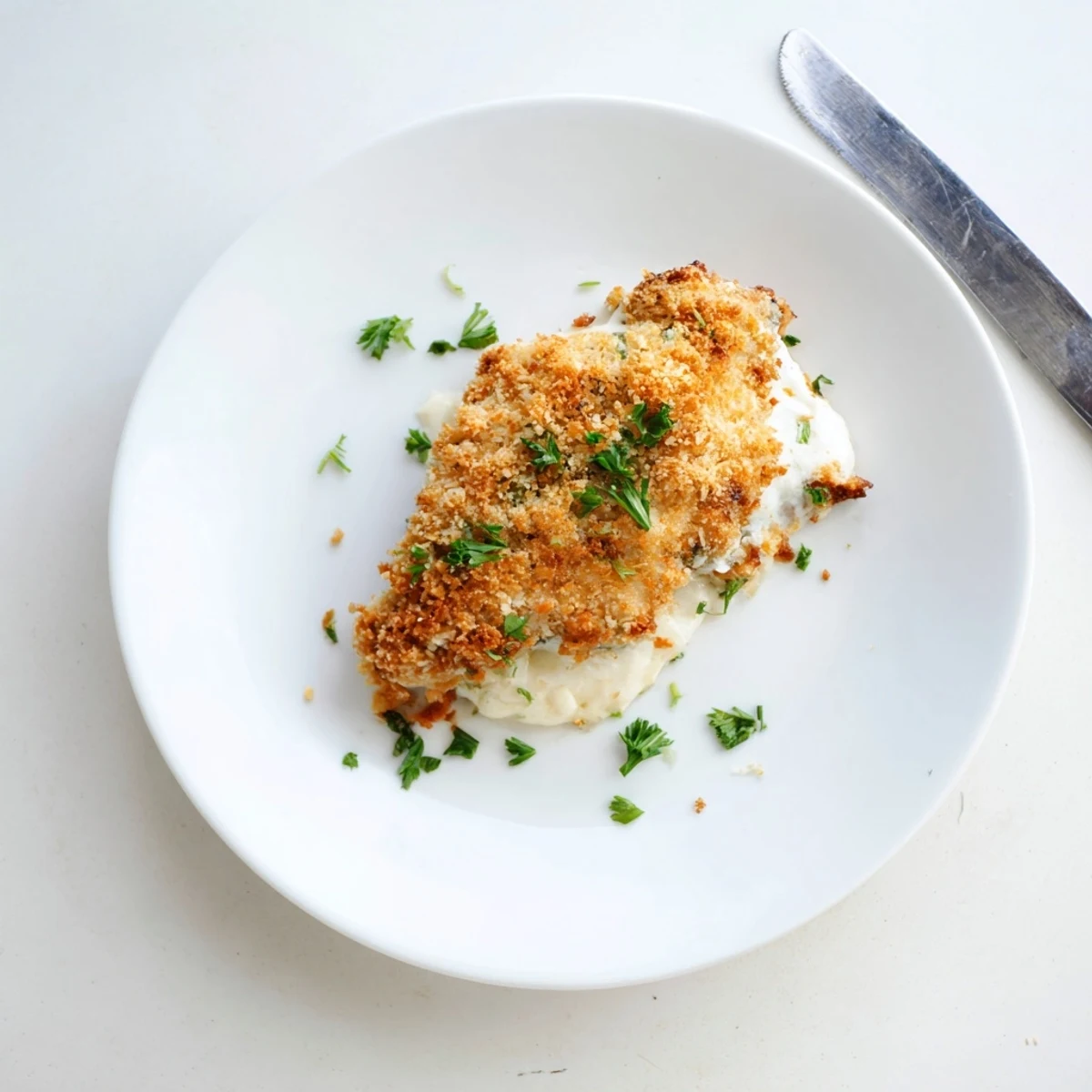 Freshly baked Longhorn Steakhouse Parmesan Crusted Chicken served with creamy mashed potatoes and a garnish of fresh parsley on a rustic wooden table.