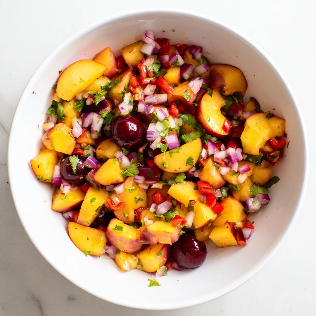 Bright, chopped Healthy Peach Cherry Salsa in a bowl, juicy peaches and sweet cherries with red onion and cilantro, ready to serve with tortilla chips.