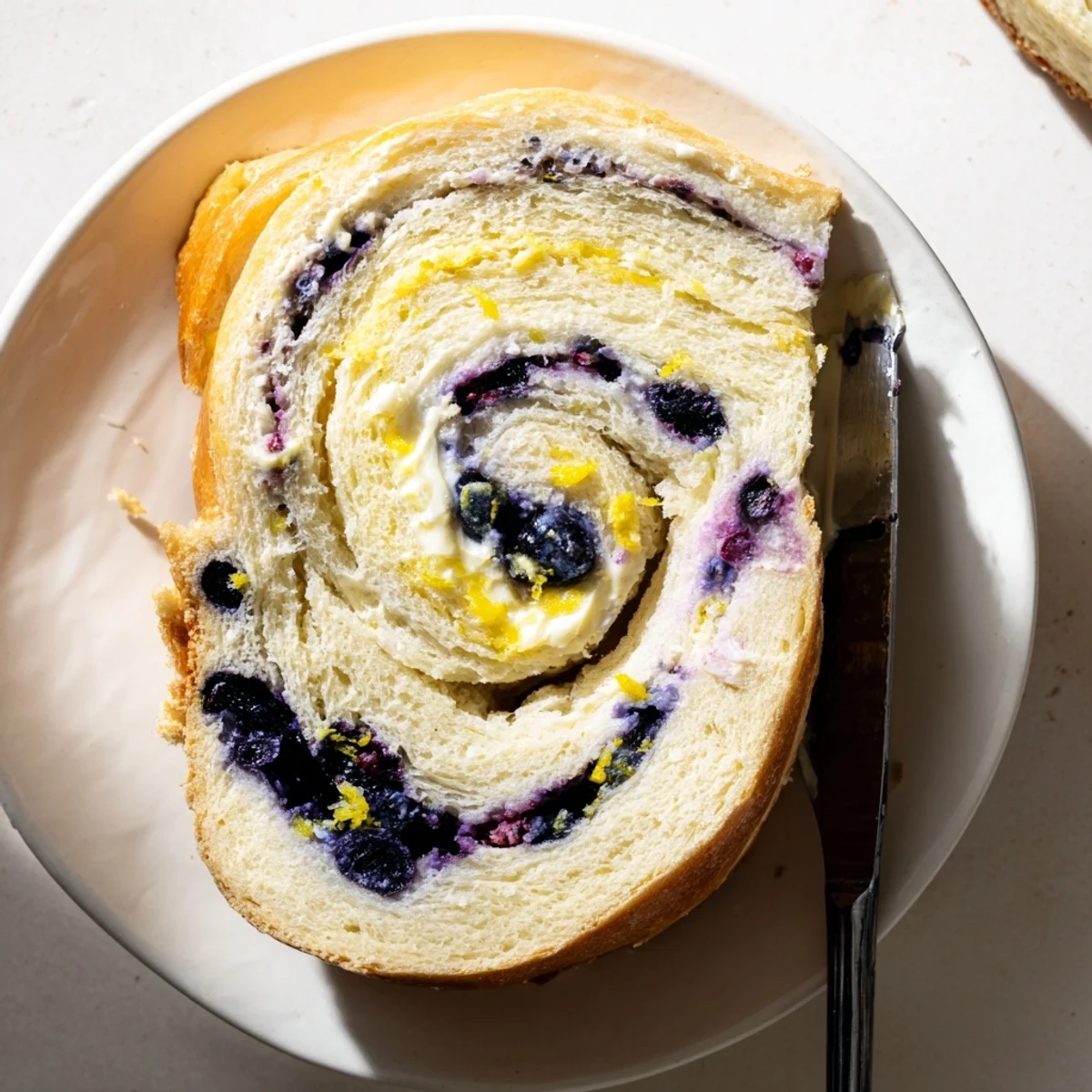 Golden baked Blueberry Lemon Cream Cheese Sourdough loaf with lemon zest topping and blueberry speckles.