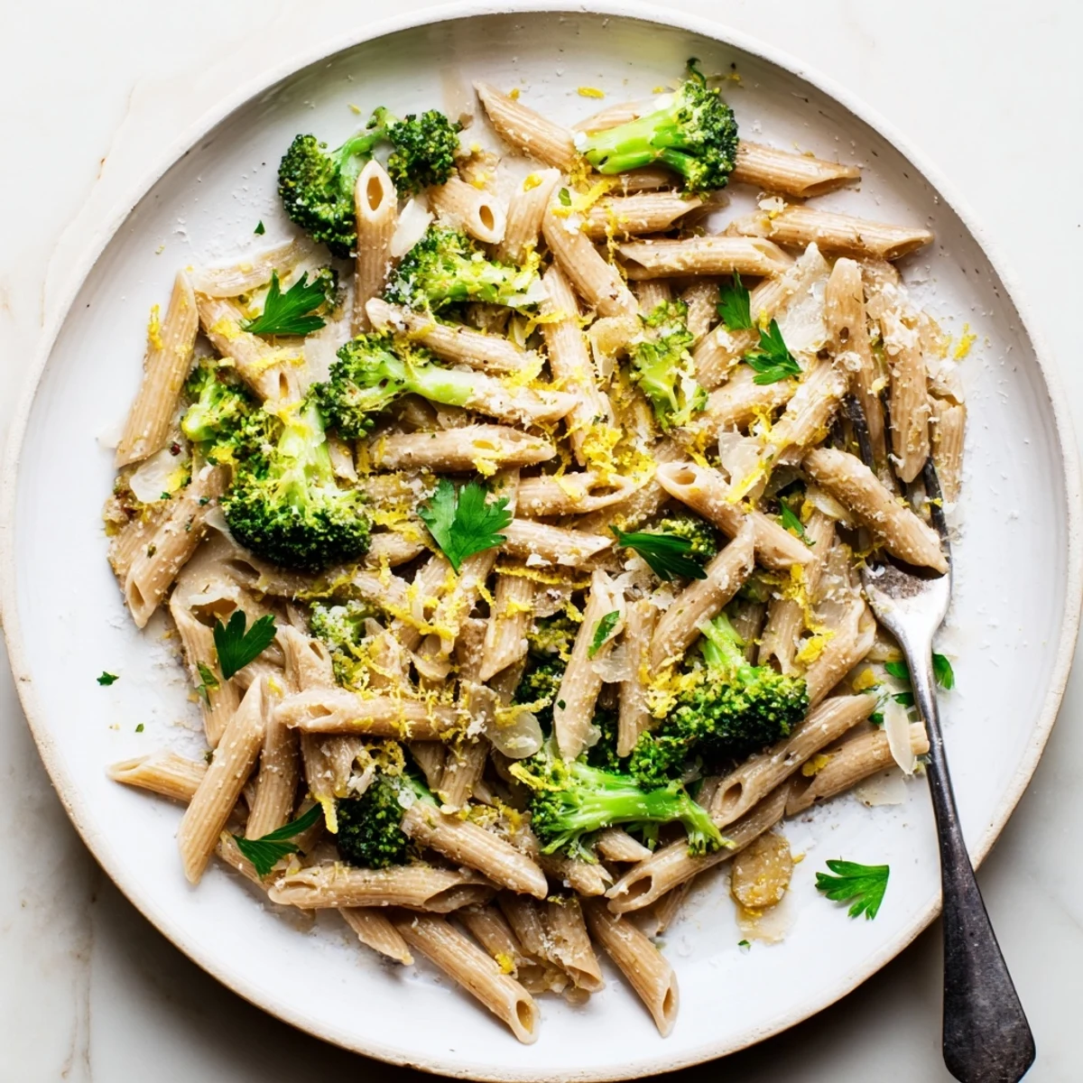 A close-up view of a warm serving of Easy Healthy Broccoli Pasta featuring tender green vegetables and al dente noodles on a rustic wooden table.
