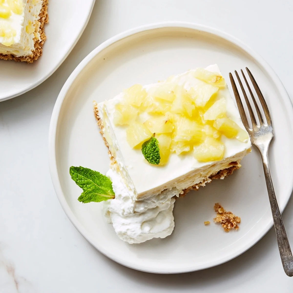 Creamy no bake pineapple cheesecake with buttery graham cracker crust and fresh mint garnish.