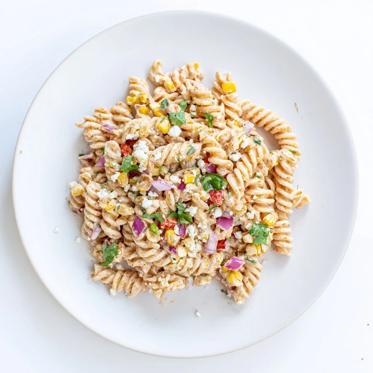 Close-up of Juicy Street Corn Pasta Salad featuring juicy corn kernels, peppers, and spicy garnish.