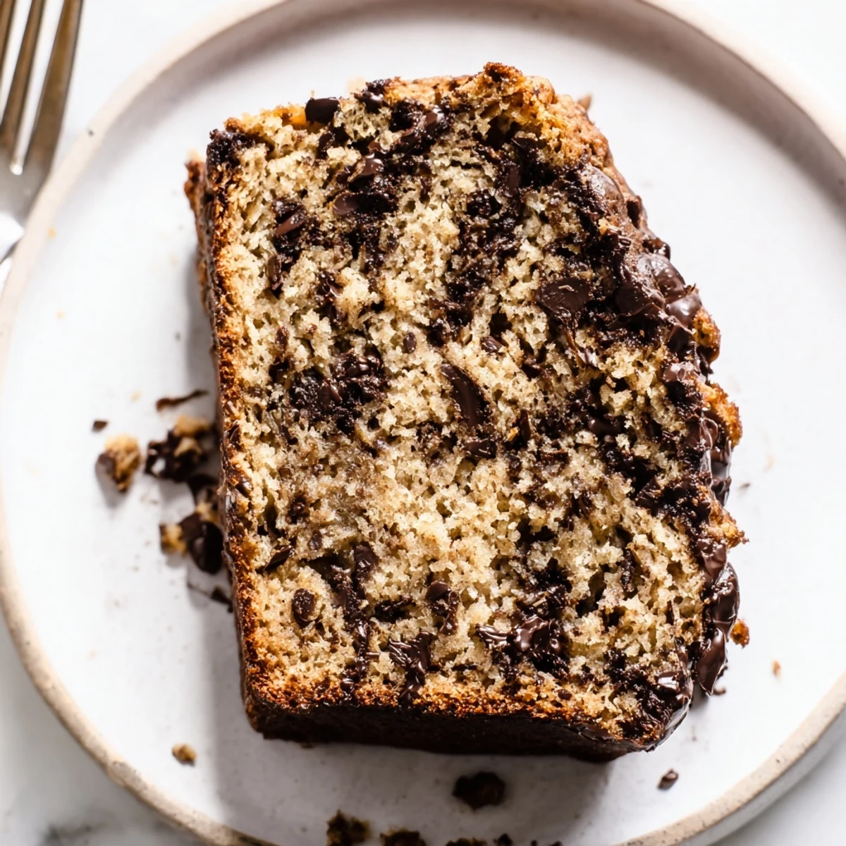 Freshly baked chocolate chip banana bread cooling on wire rack with shiny melted chocolate chips visible