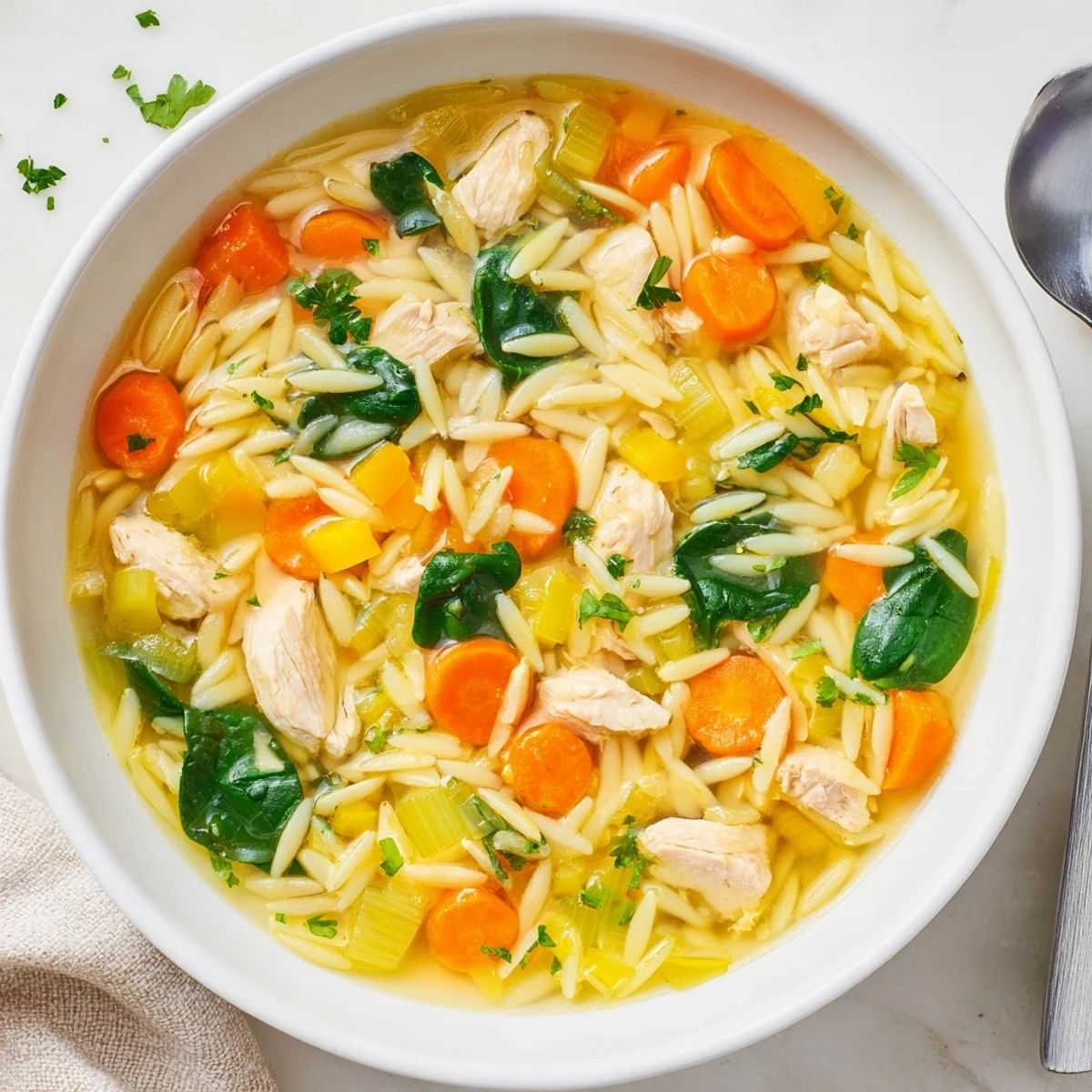 Comforting Spring Lemon Chicken Orzo Soup with wilted spinach, diced carrots, and plump orzo in a light lemony chicken broth