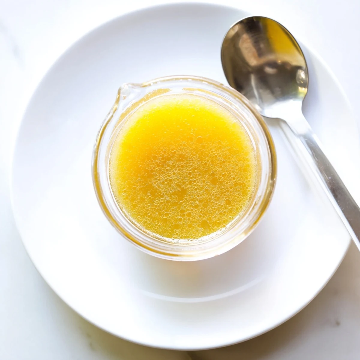 Golden honey lemon vinaigrette drizzled over fresh mixed greens in a white bowl