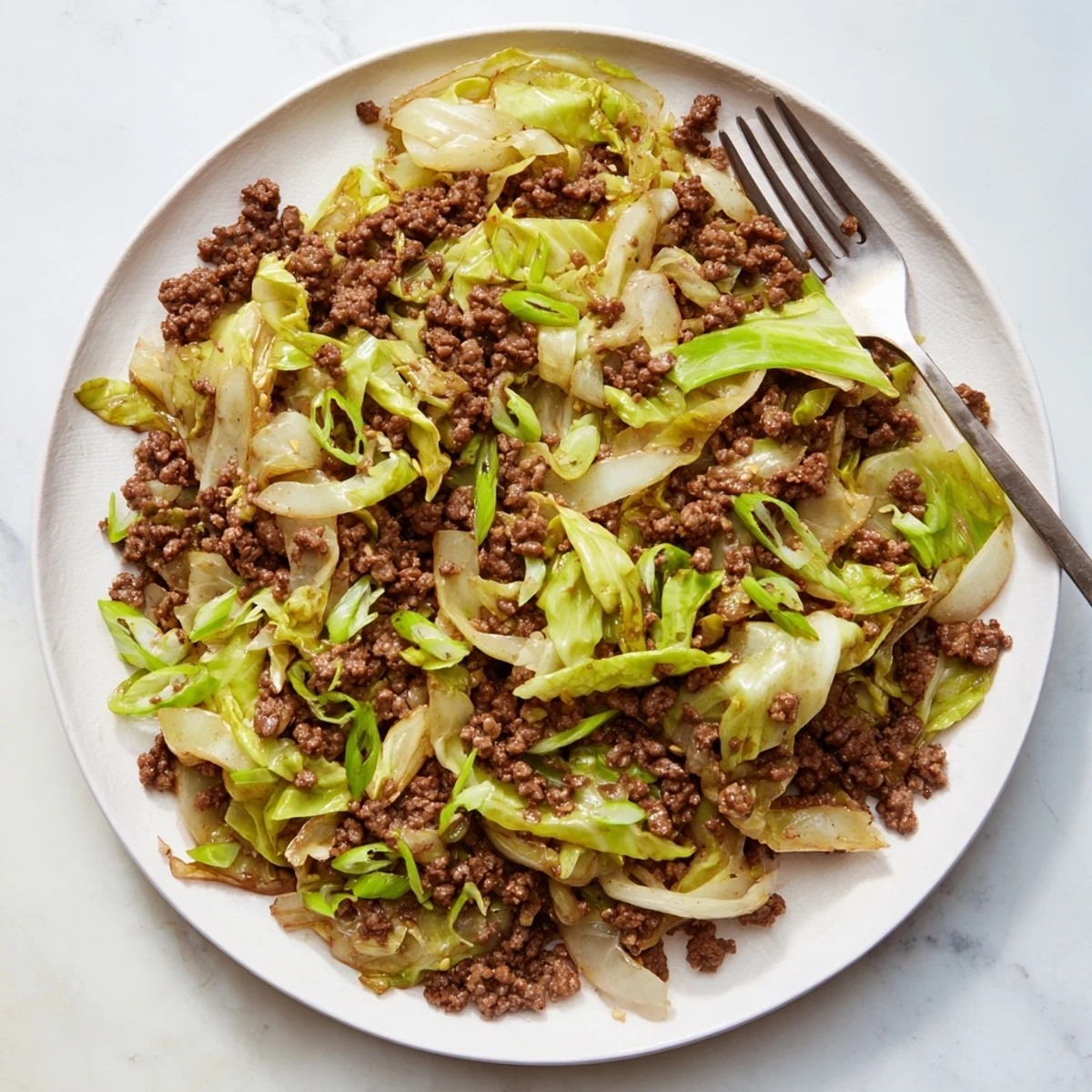 Sizzling skillet of low-carb Mongolian ground beef and cabbage with caramelized onions and glistening Asian-inspired sauce, perfectly plated for a satisfying weeknight dinner