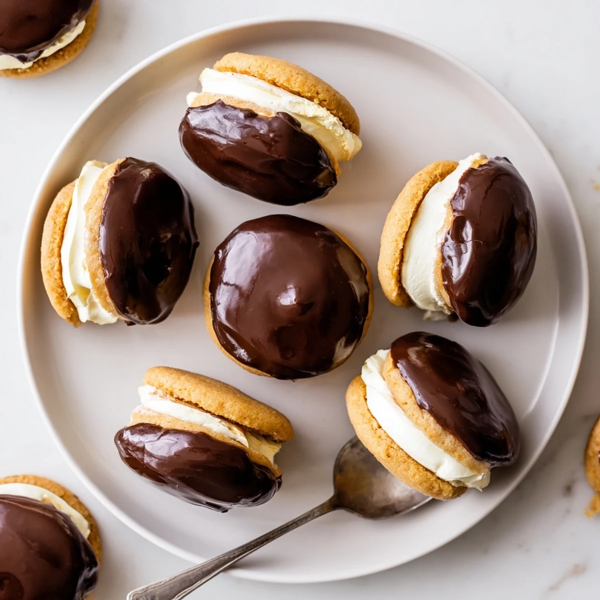 Golden vanilla cookie sandwiches filled with creamy custard and topped with rich chocolate glaze in these Boston cream pie cookie bites