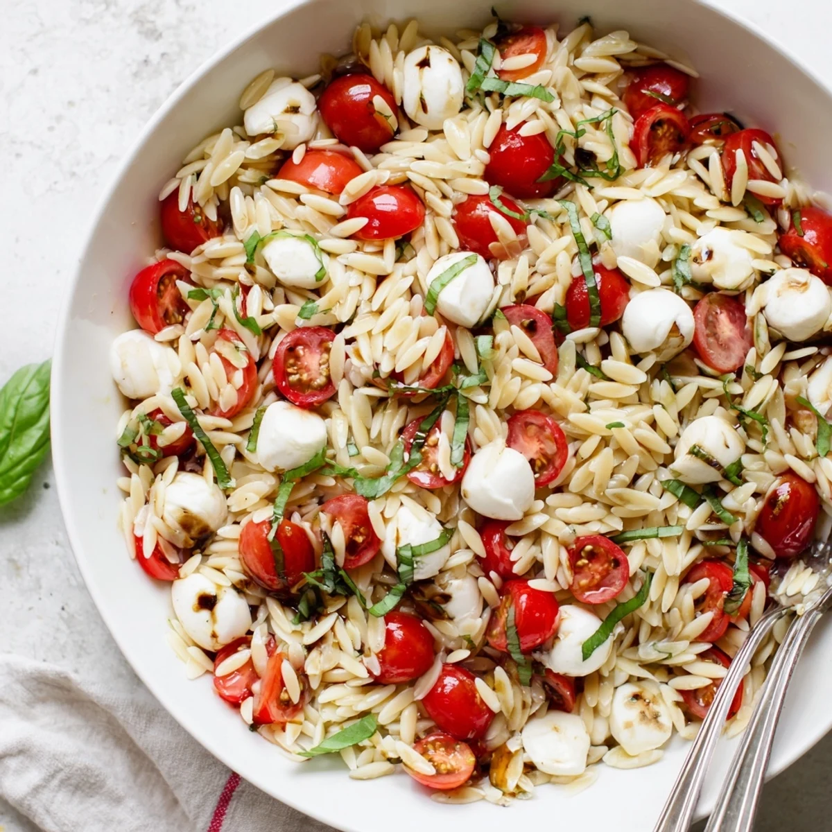Refreshing summer Caprese orzo pasta salad with tender pasta, halved mozzarella, and vibrant red tomatoes