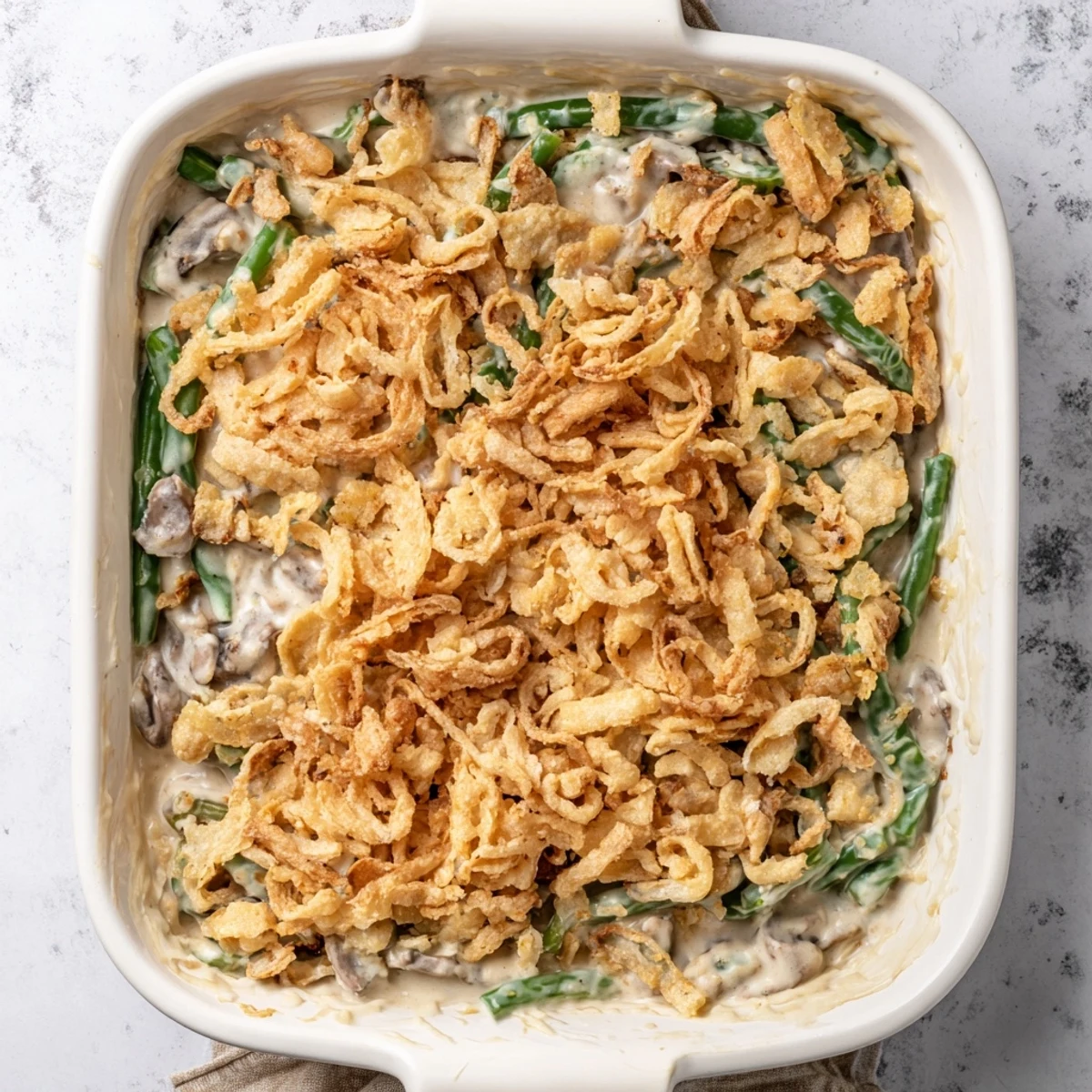 Golden green bean casserole with creamy mushroom sauce and buttery Ritz cracker topping bubbling in a baking dish