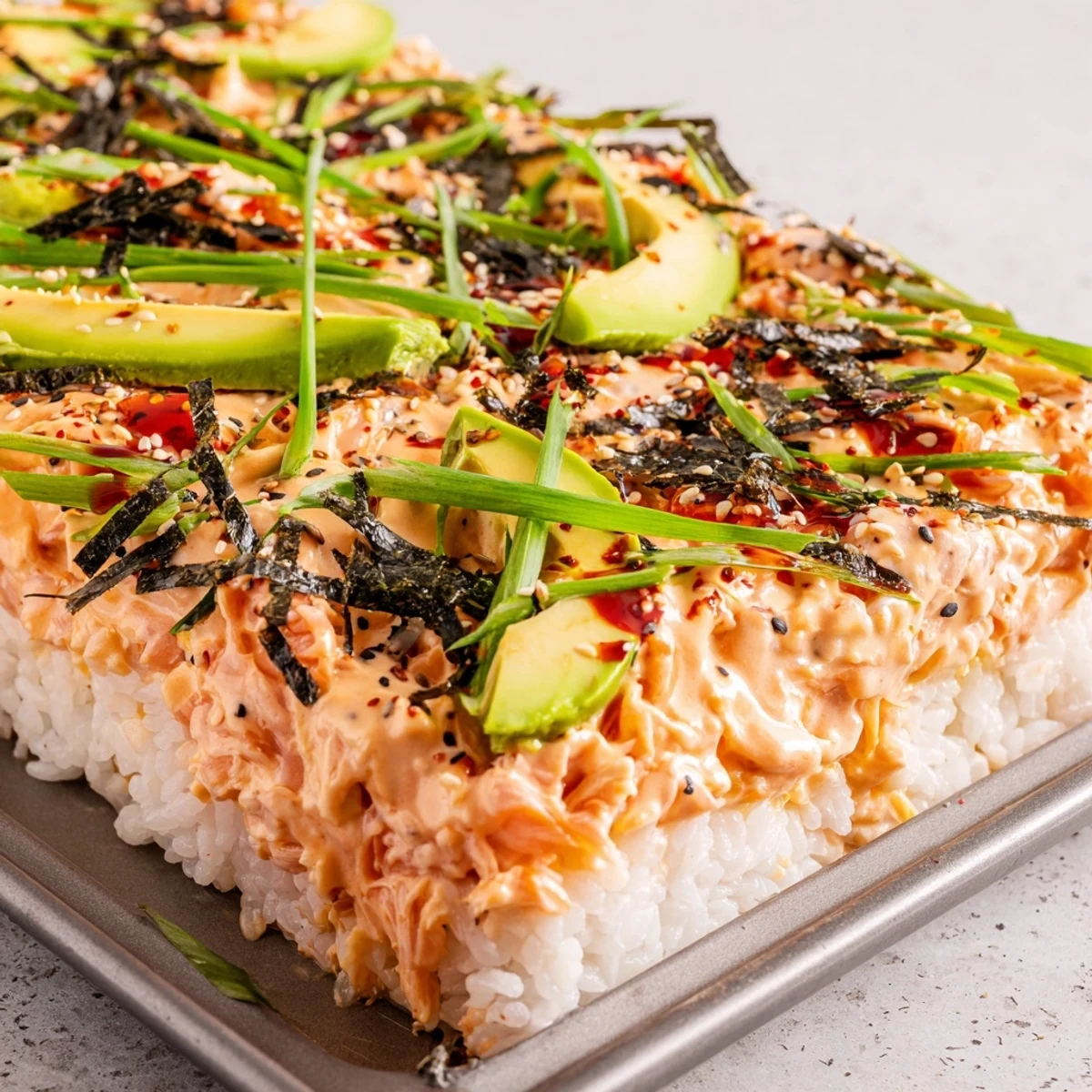 Bubbling hot salmon sushi bake with furikake seasoning and green onion garnish on rice