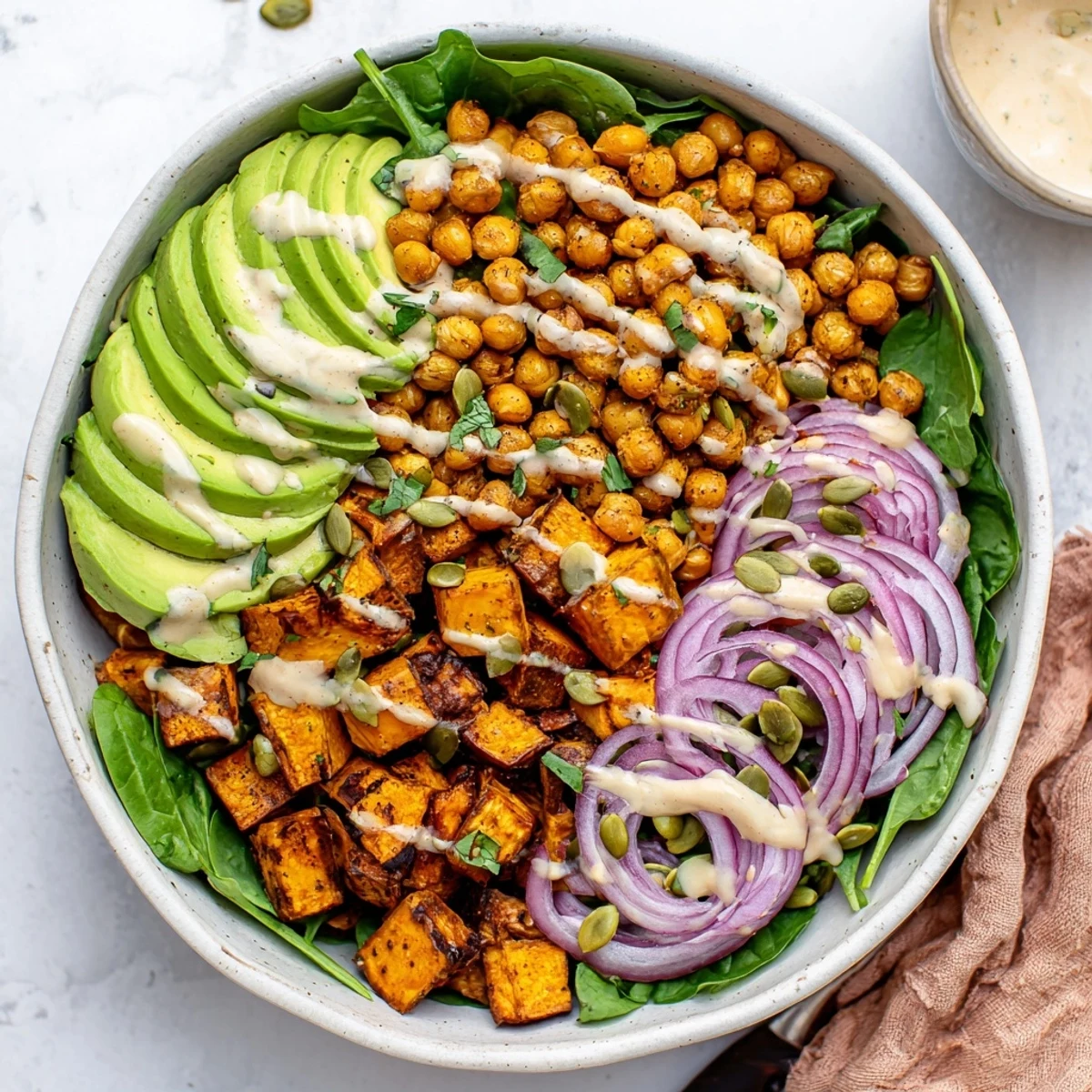 Wholesome roasted sweet potato and chickpea grain bowls topped with zesty tahini sauce and pumpkin seeds