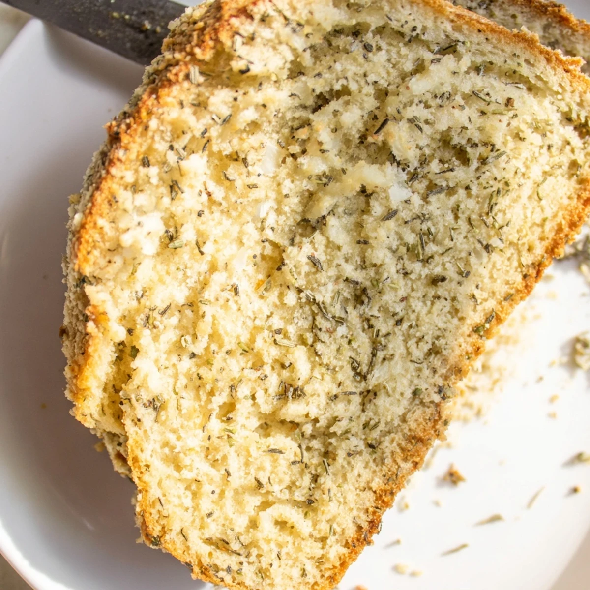 Golden Parmesan herb keto bread loaf sliced on a wooden cutting board with fresh parsley garnish