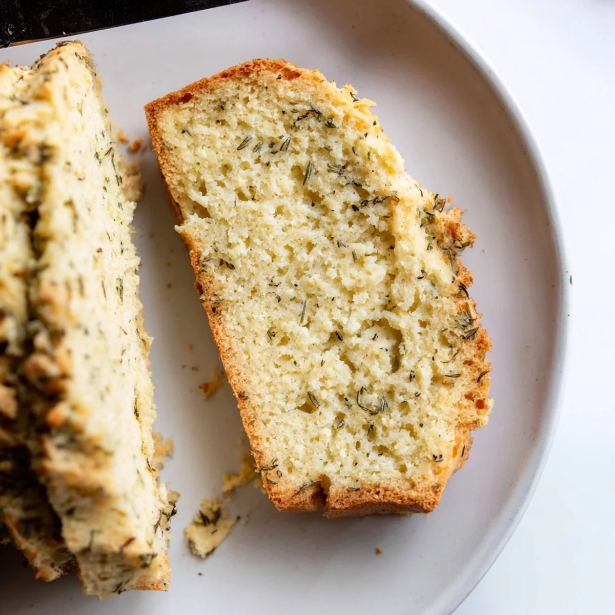 Savory gluten-free Parmesan herb keto bread showing a thick slice with visible herbs and golden crust