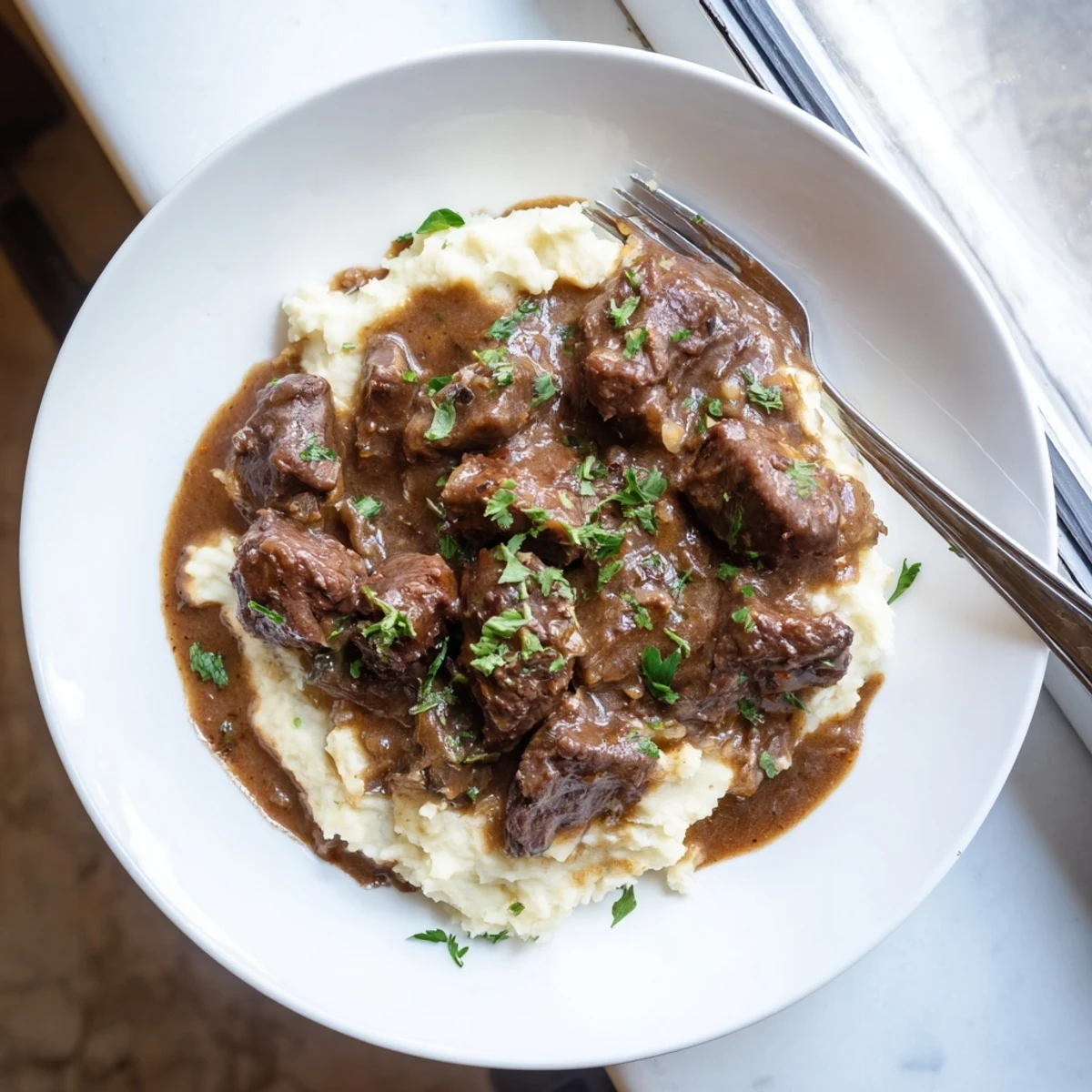 Fork-tender slow cooker beef tips and gravy ladled over white buttery noodles