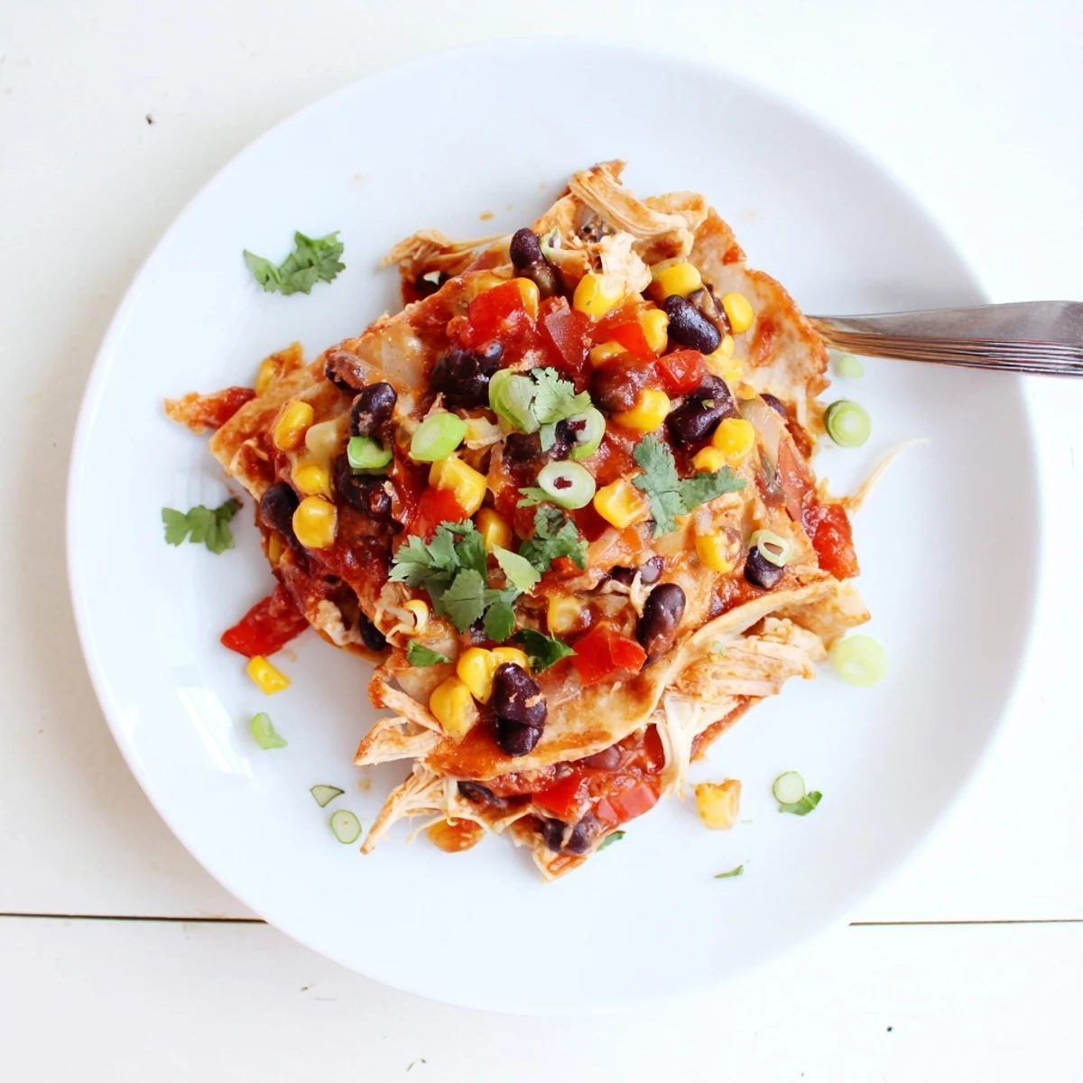 Slow cooker chicken enchilada casserole layered with melted cheese, tortillas, and colorful vegetables