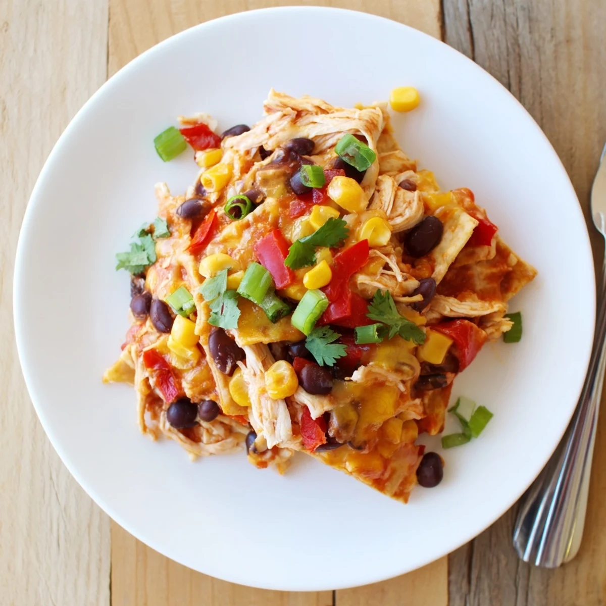 Serving of Crockpot chicken enchilada casserole topped with fresh cilantro and sour cream garnish