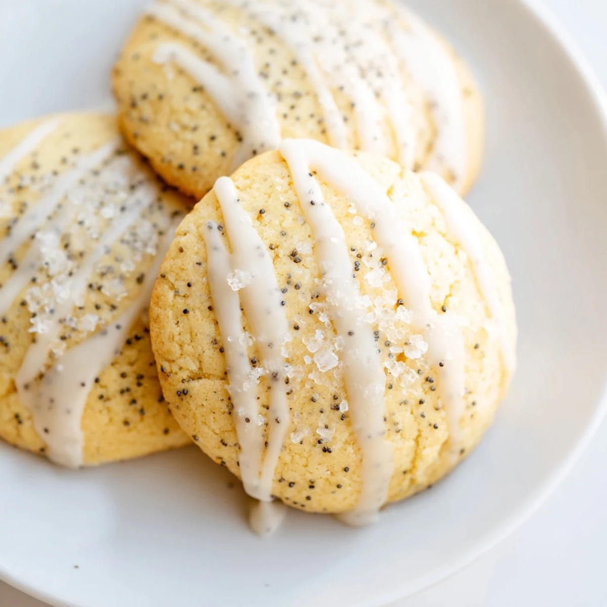 Golden lemon poppy seed cookies with crackly tops drizzled with sweet citrus glaze on a rustic wooden board