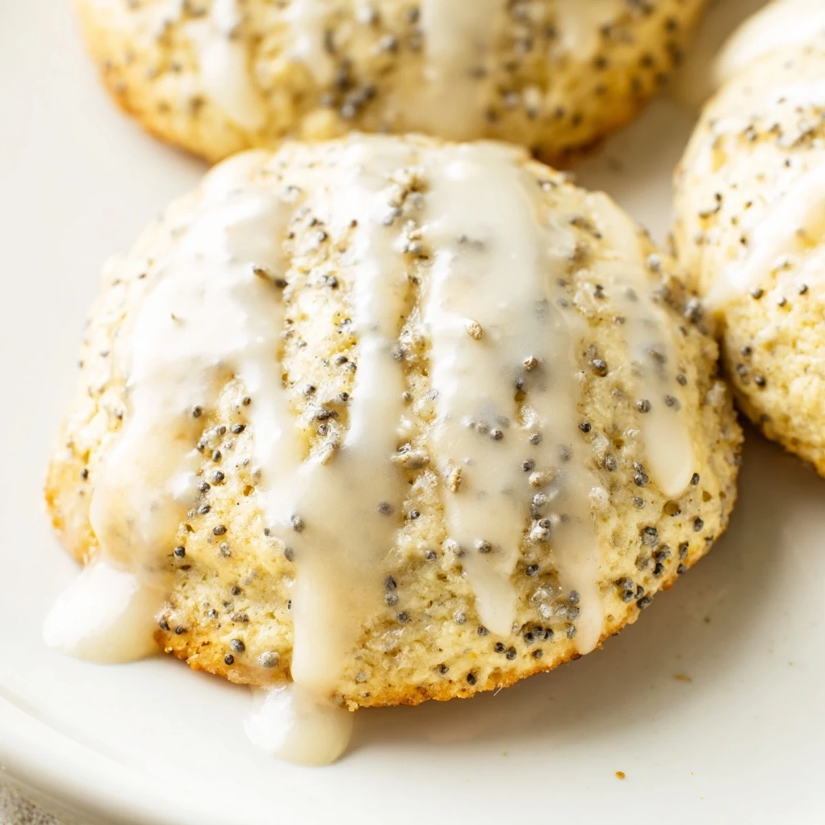 Chewy lemon poppy seed cookies speckled with tiny black seeds arranged on a white ceramic serving plate