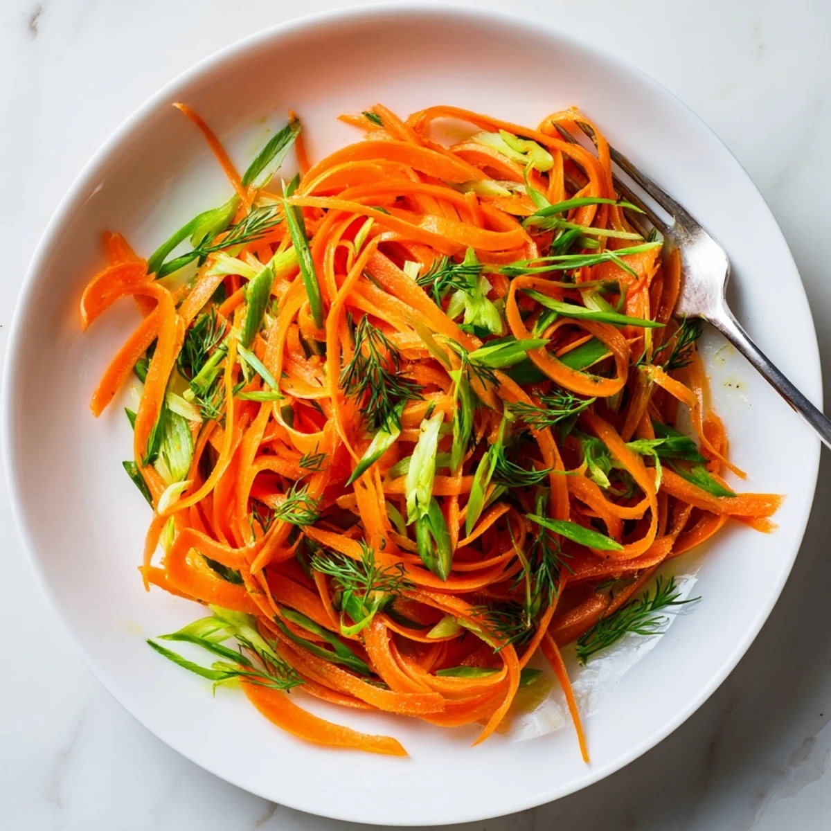Bright lemon dill carrot salad with fresh herbs on a white plate