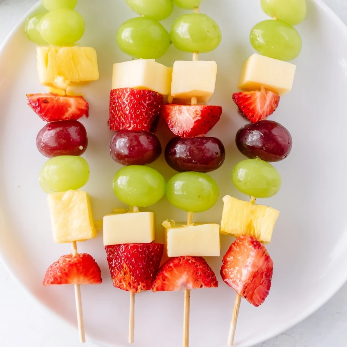 Fruit and cheese kabobs arranged on platter with colorful grapes strawberries and cheddar cubes