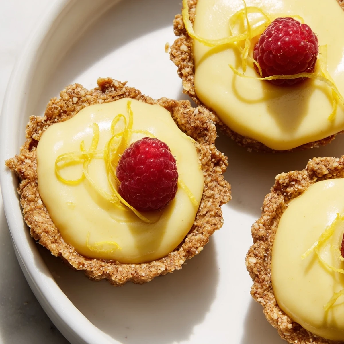 Luscious mini vegan lemon tarts garnished with lemon zest and edible spring flowers