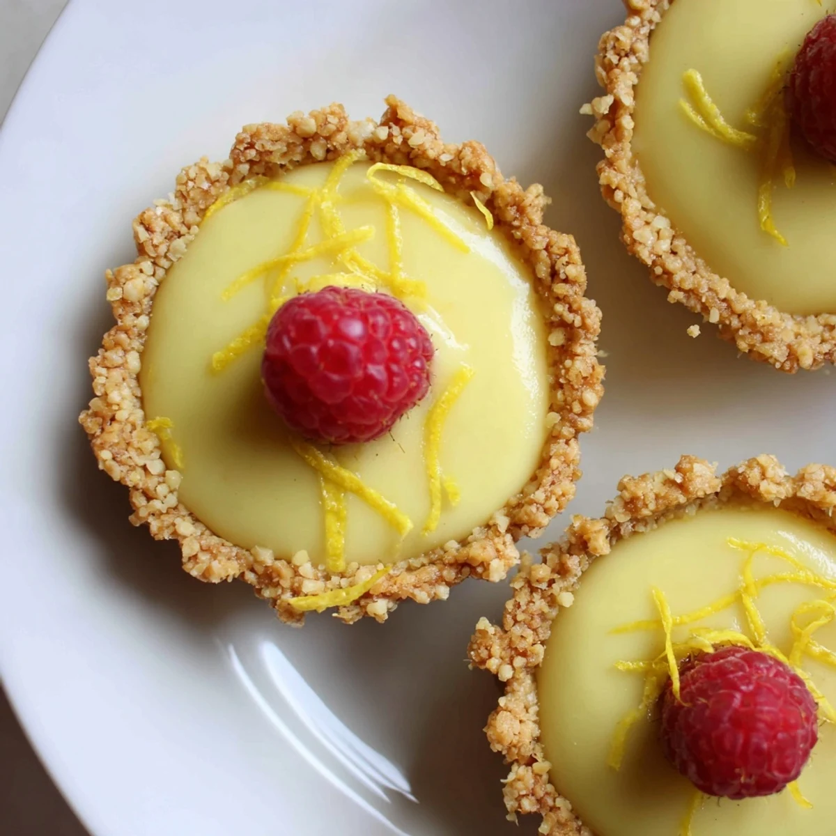 Creamy mini vegan lemon tarts in crisp almond crusts dusted with powdered sugar