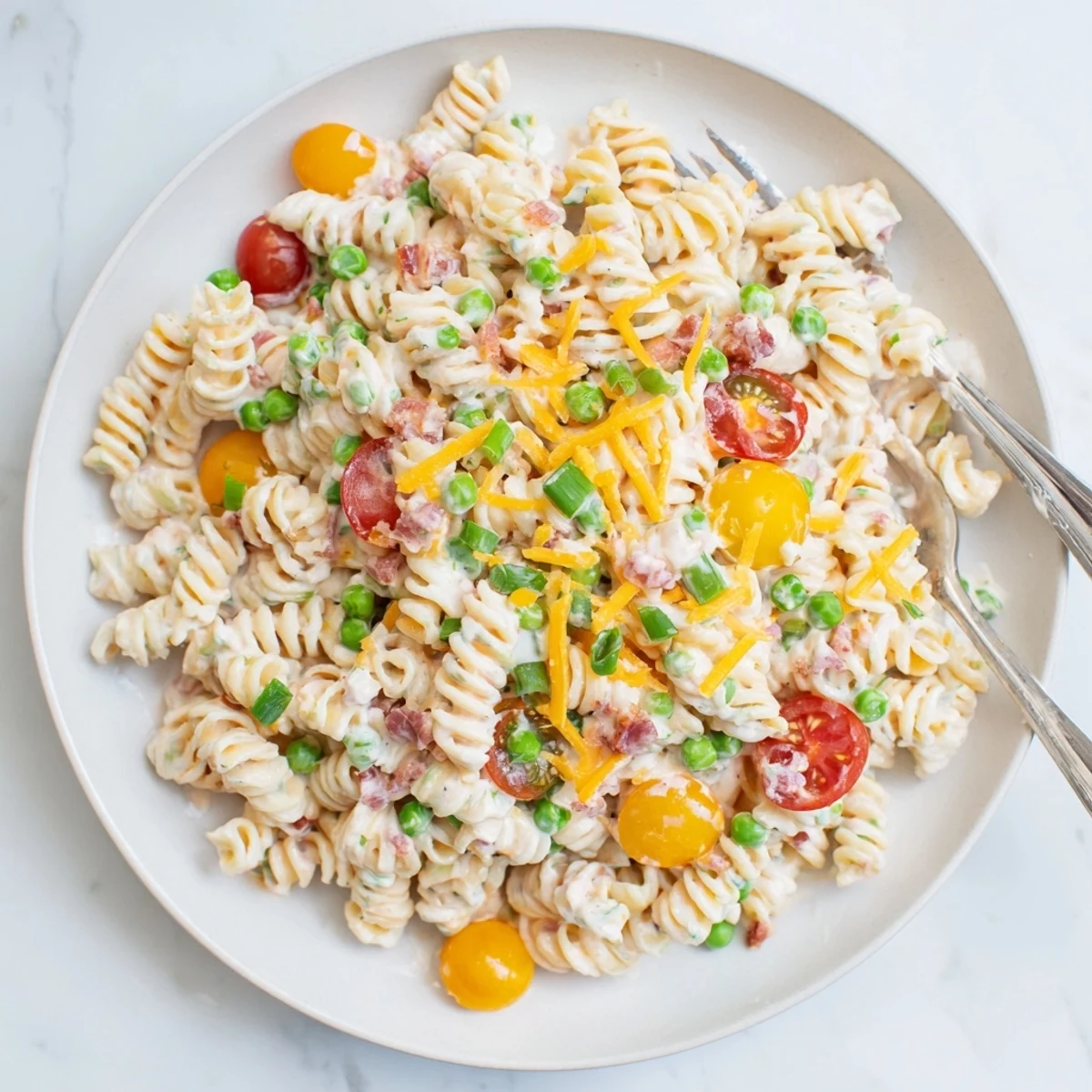 Colorful crack pasta salad mounded in a bowl with cherry tomatoes and crispy bacon bits