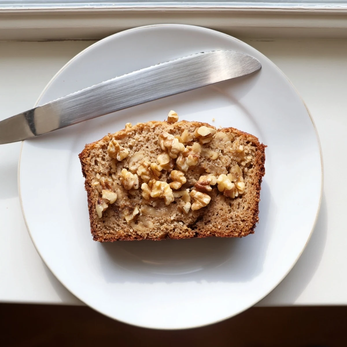 Golden banana nut bread loaf topped with crunchy walnuts on a wire rack