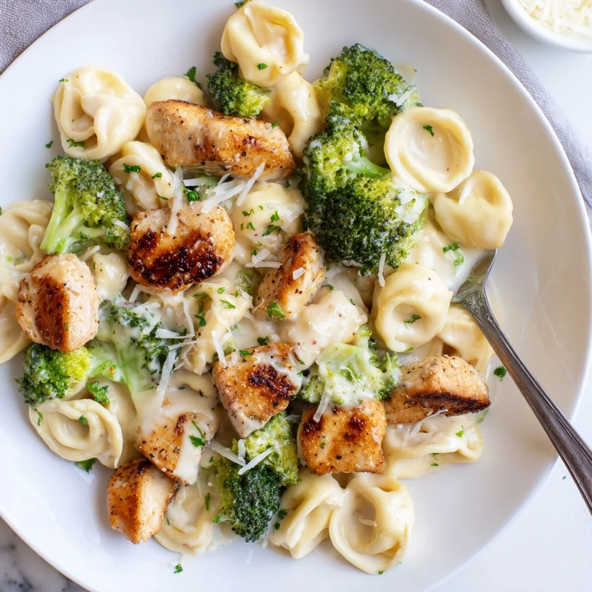 Steaming skillet tossed in rich sauce, showcasing Creamy Garlic Parmesan Tortellini Chicken Broccoli Recipe.