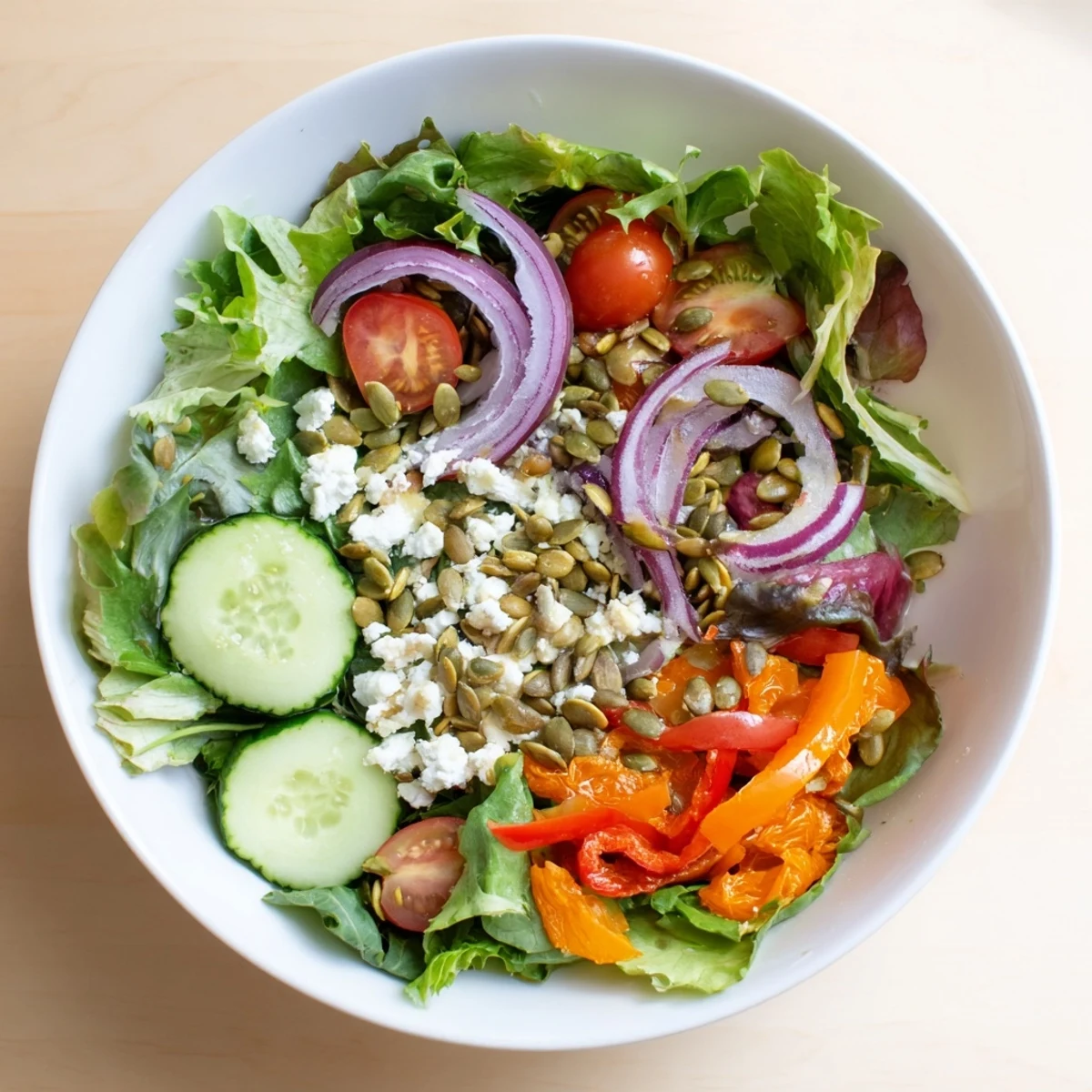 Colorful garden salad bowl with crisp mixed greens, cherry tomatoes, cucumber, and light vinaigrette dressing drizzled on top