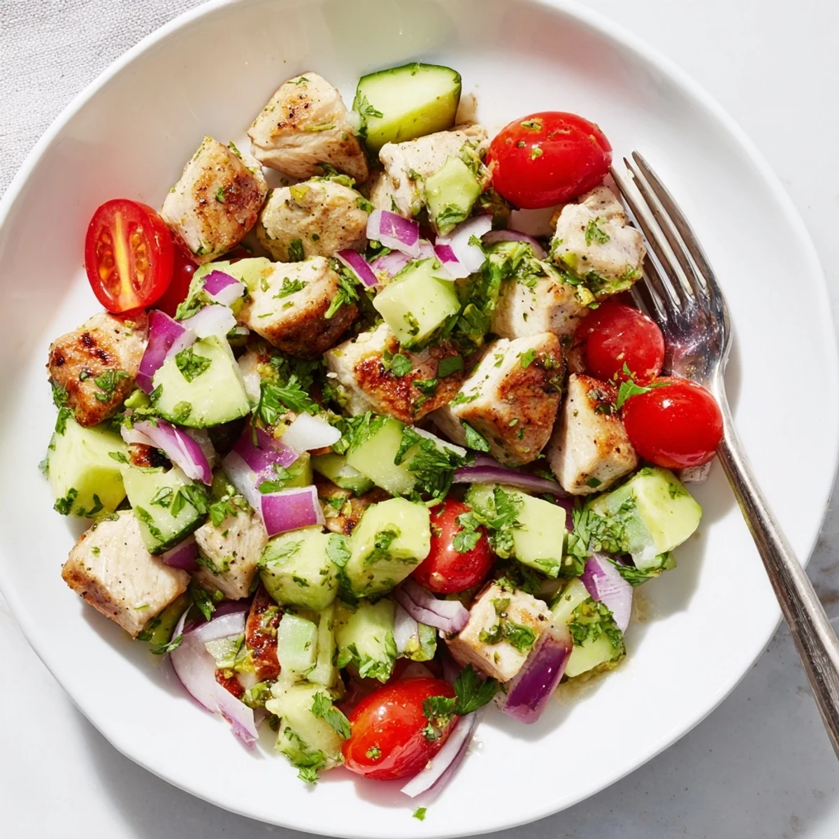 Fresh healthy avocado chicken salad bowl with grilled chunks, ripe avocado, cherry tomatoes, and lime dressing