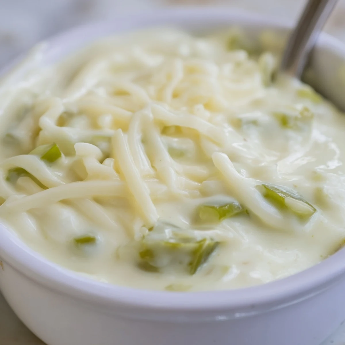Gooey white queso dip topped with fresh jalapeño slices alongside colorful tortilla chips for sharing